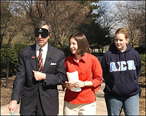 Dr. Geoffroy with blindfold on and can walking on central
campus
