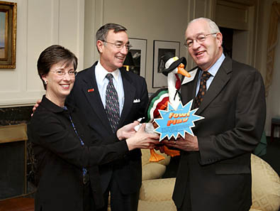 Dr. and
Mrs. Geoffroy giving Dr. Madden the University Child Care traveling mascot.