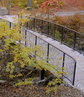 A concrete walking bridge with iron railings