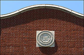 university seal on side of a building with a curved
roof