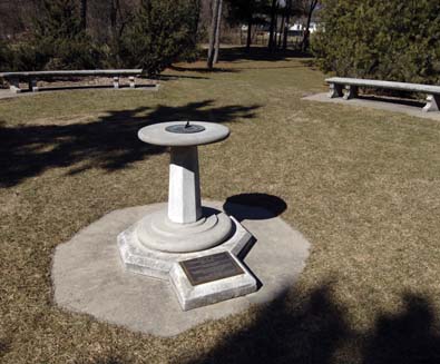 Large sundial on a pedestal in a grassy area