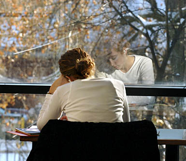 A student is reflected in the window at Parks Library